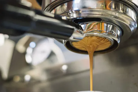 Frischer Espresso fließt aus dem Siebträger einer Espressomaschine